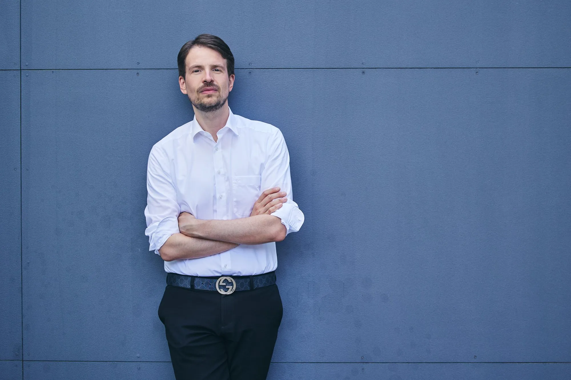 Prof. Dr. Jürgen Weimann an eine blaugraue Wand gelehnt
