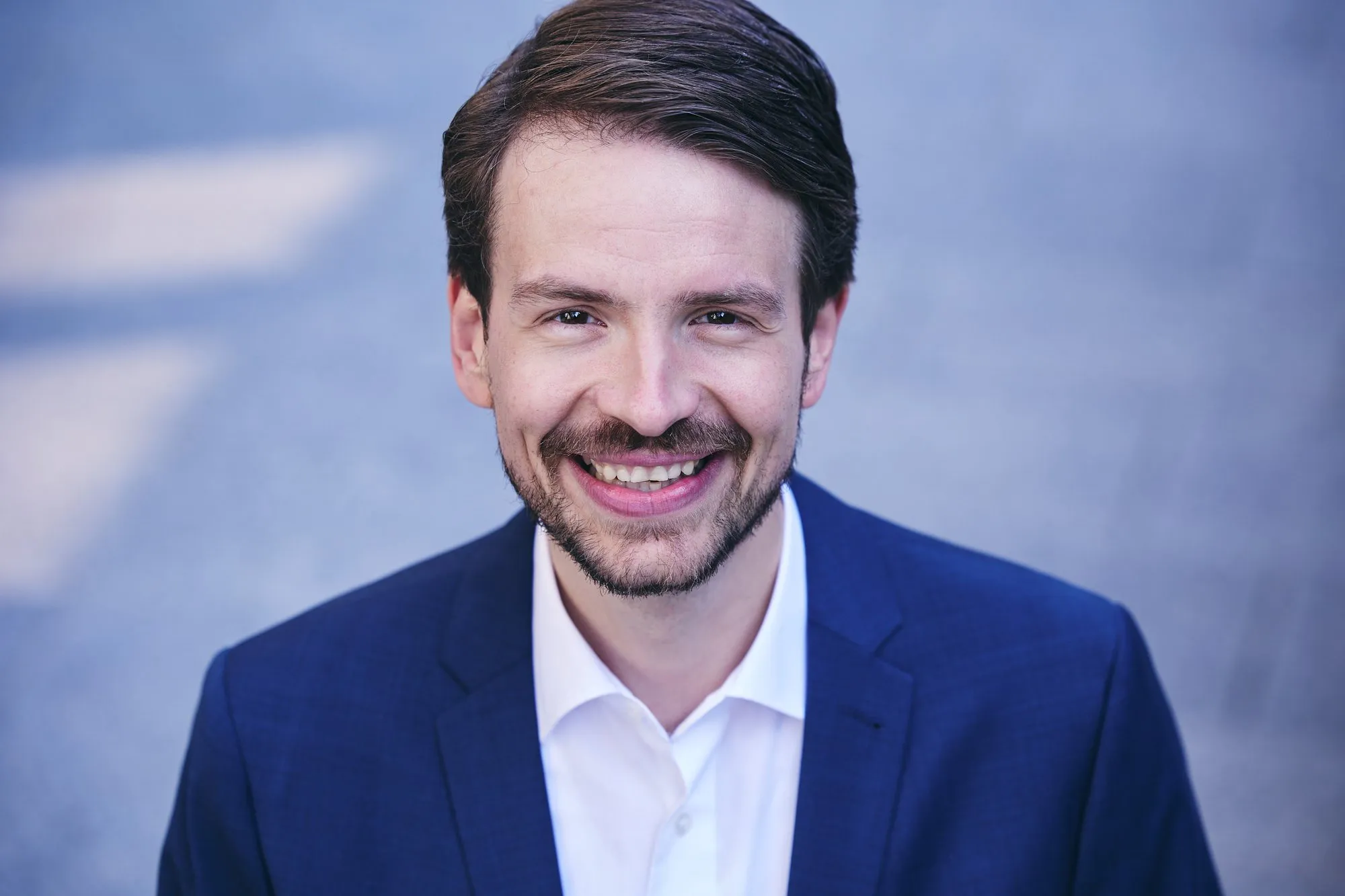 Prof. Dr. Jürgen Weimann lachend im blauen Anzug