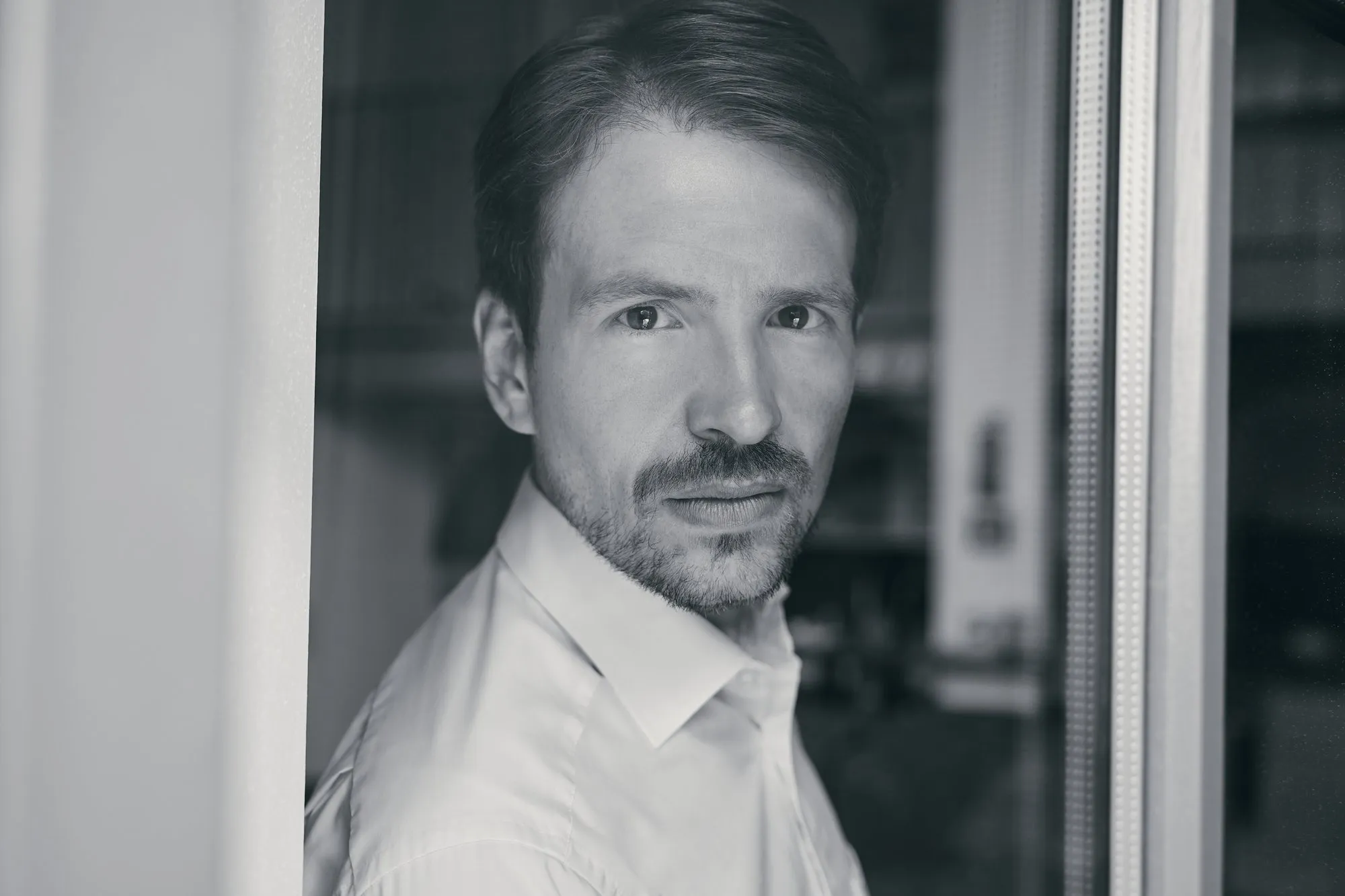 Schwarz-Weiß-Porträt Prof. Dr. Jürgen Weimann am Fenster